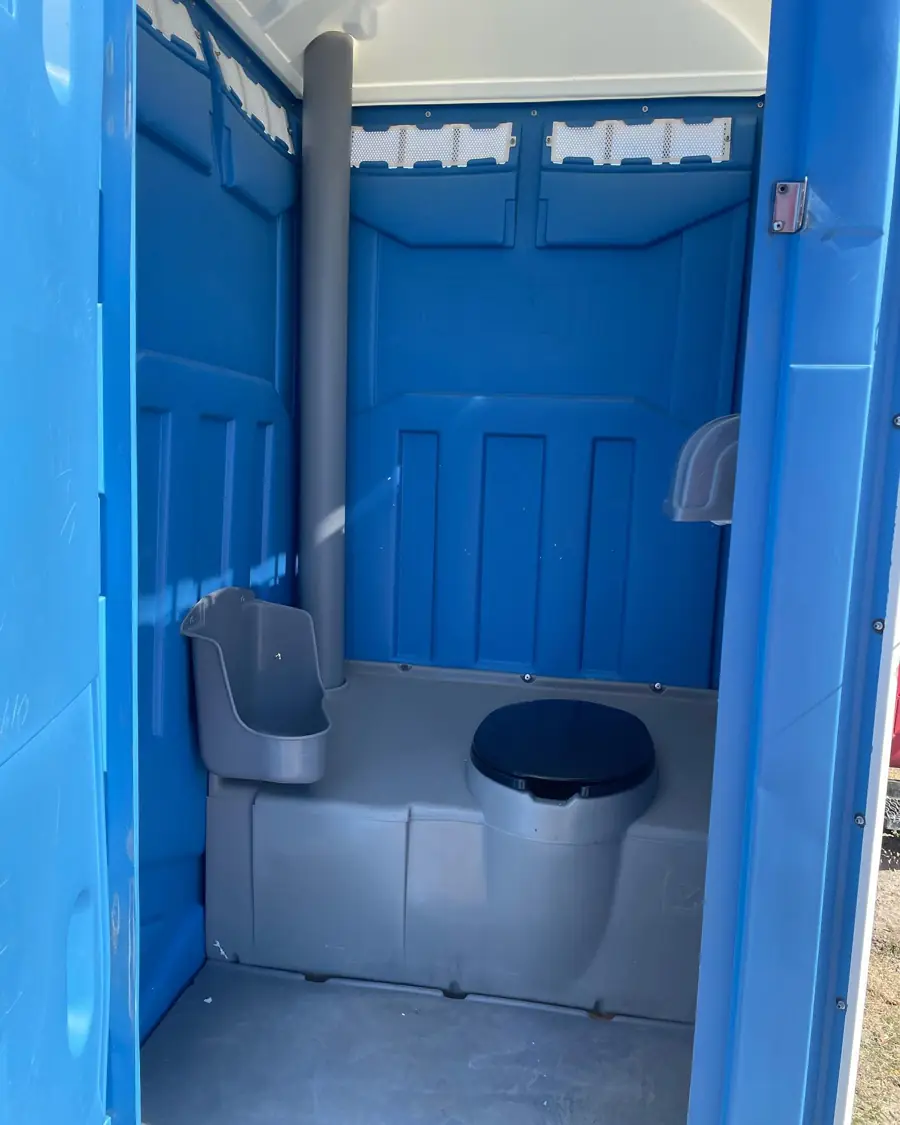 Interior of a blue portable toilet with seat, urinal and vent pipe