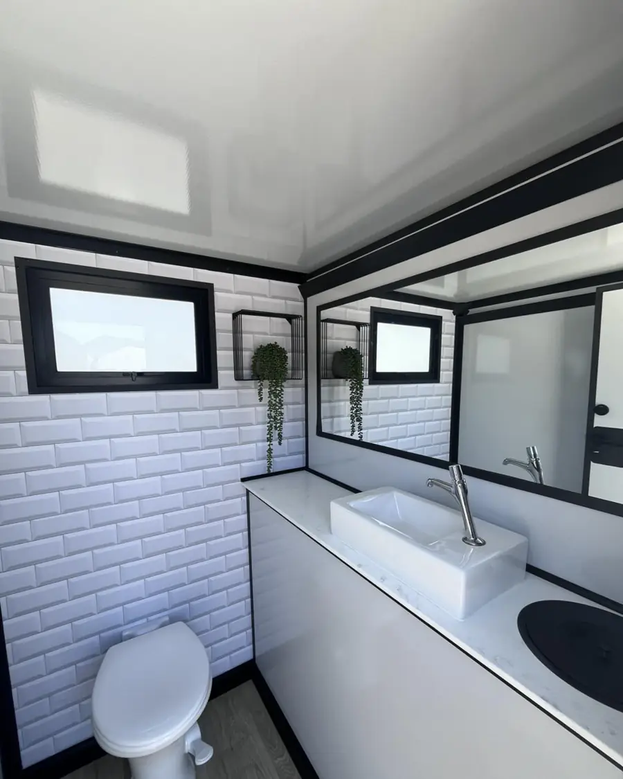 Tiled restroom trailer interior with porcelain toilet and vanity