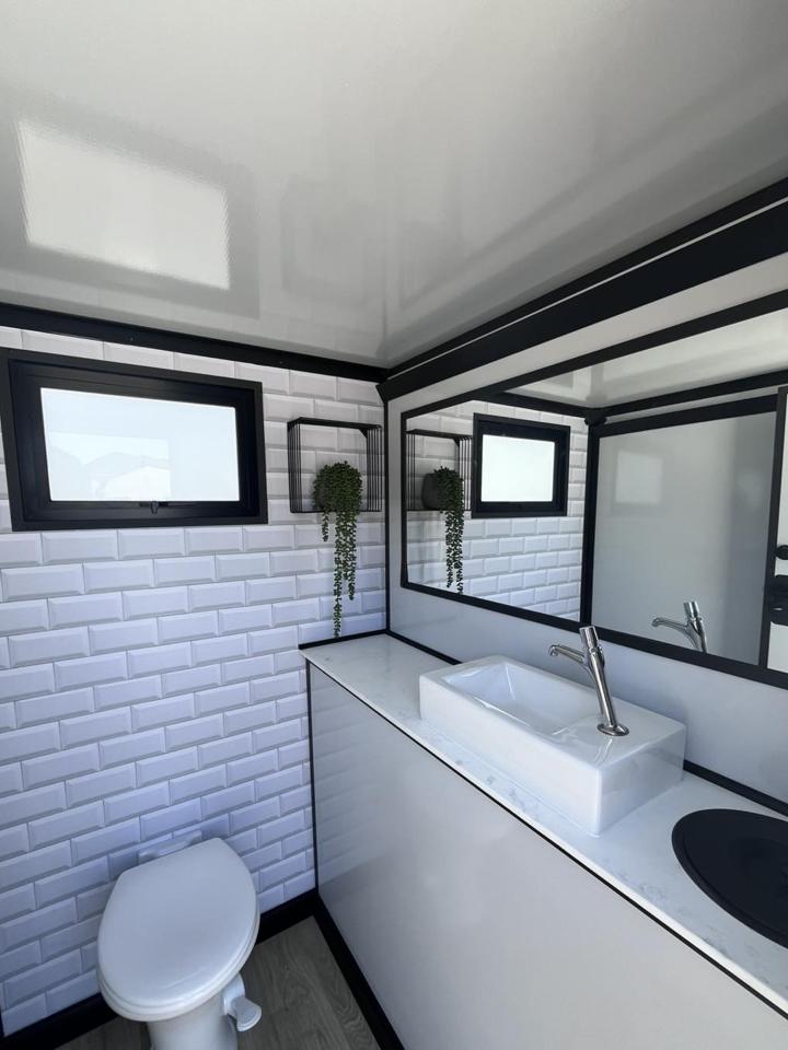 Tiled restroom trailer interior with porcelain toilet and vanity